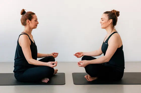 Yoga-Übung mit Korrektur durch die Trainerin